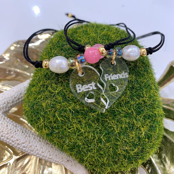 Hermoso set de 2 pulseras confeccionadas a mano con charm de acrílico en forma de corazón dividido con la palabra Best Friends y montadas en hilo de nylon ajustable. Además también incluyen una perla original de agua dulce y un cuarzo ágata. Excelente joyería para regalar a tu mejores amig@s. Este set tiene un bello y único estilo para hacerlas lucir únicas y más unidas. Sus separadores plateados son en  baño en plata u oro.  Resistentes al agua.