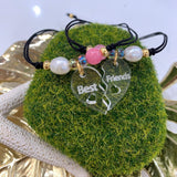 Hermoso set de 2 pulseras confeccionadas a mano con charm de acrílico en forma de corazón dividido con la palabra Best Friends y montadas en hilo de nylon ajustable. Además también incluyen una perla original de agua dulce y un cuarzo ágata. Excelente joyería para regalar a tu mejores amig@s. Este set tiene un bello y único estilo para hacerlas lucir únicas y más unidas. Sus separadores plateados son en  baño en plata u oro.  Resistentes al agua.